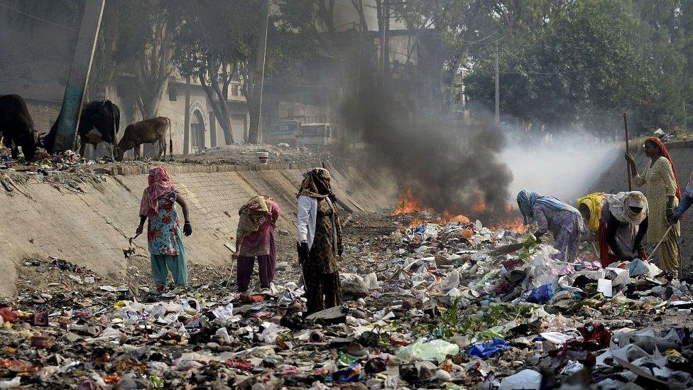 women-in-street-with-plastic-pollution-from-rubbish-brining.