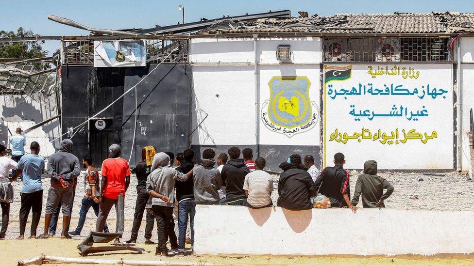 Migrants stand outside a detention centre used by the Libyan Government in the capital Tripoli