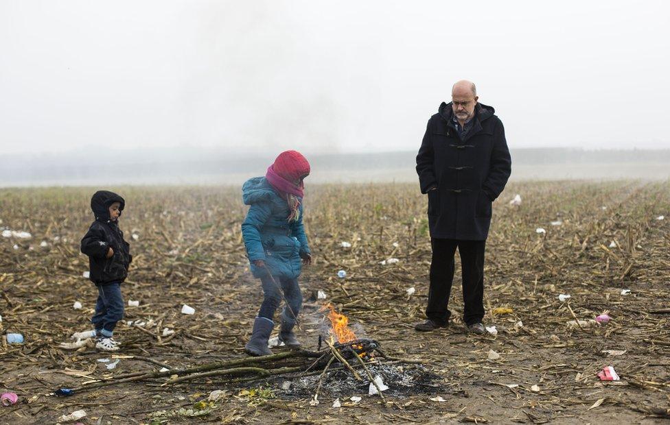 John Sweeney watches as two children play by a fire at a refugee crossing point