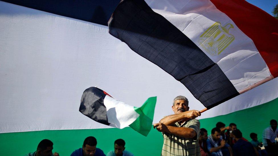 A Palestinian man waves the Egyptian and Palestinian flags as people gather in Gaza City to celebrate the signing of a reconciliation deal (12 October 2017)