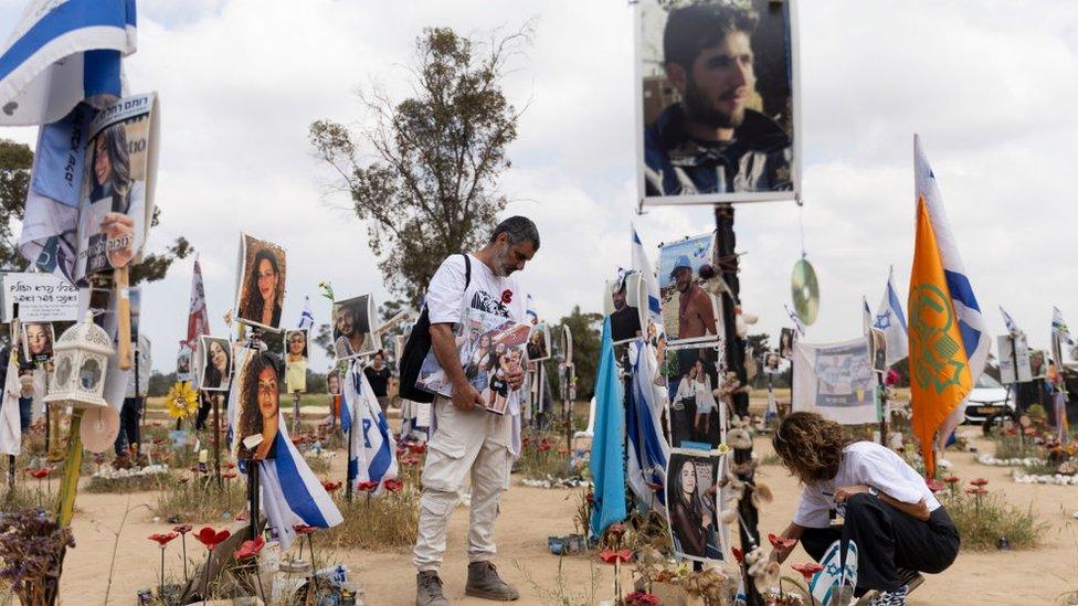 People mourn for the dead at the site of the Nova festival