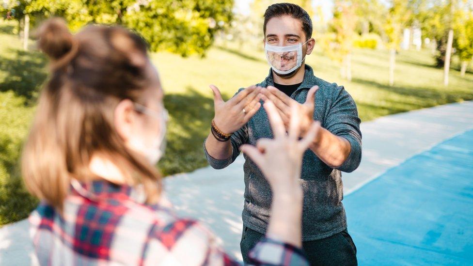 Two people wearing clear facemasks