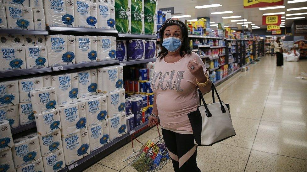 A customer poses for a photo wearing a face mask while shopping at Iceland in Islington on July 11, 2020