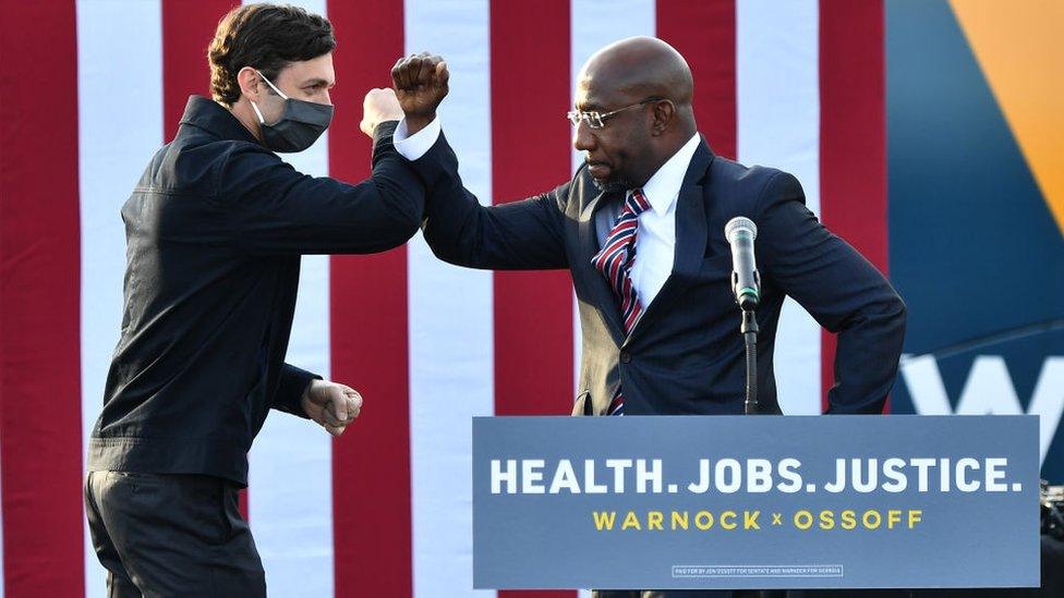 Rev Raphael Warnock greet each other Jon Ossoff onstage in Stonecrest, Georgia, on 28 December 2020