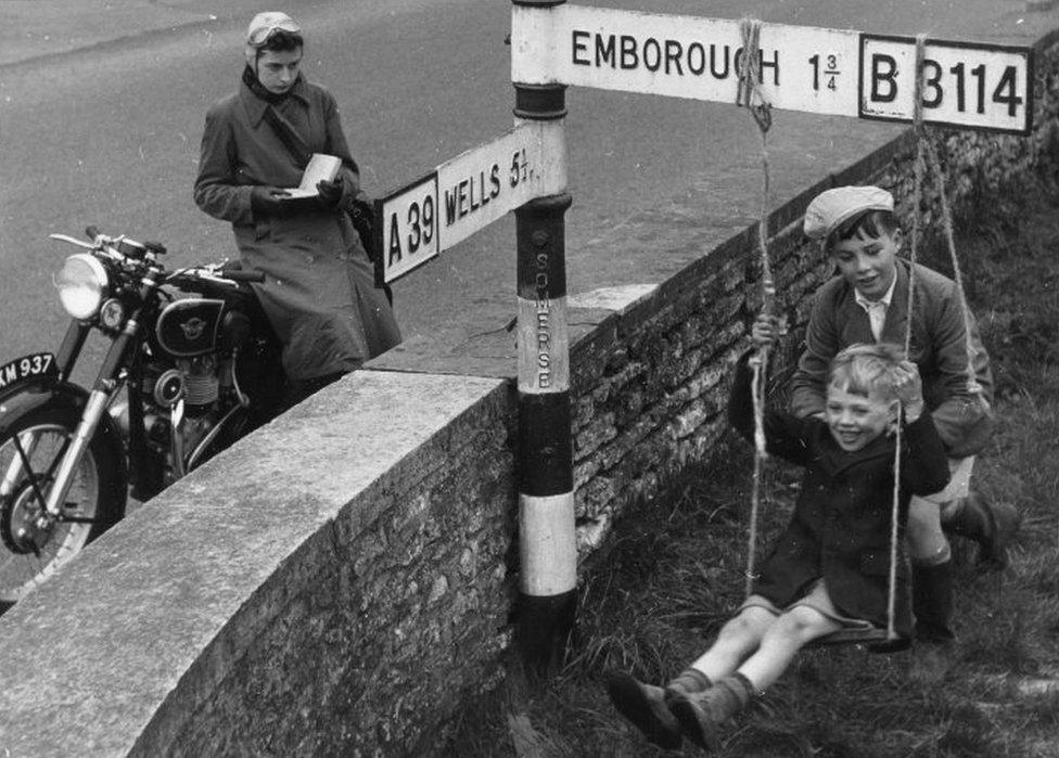 Boys swing from road sign