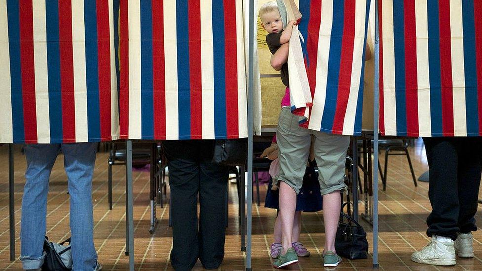 Landon Peterson peeks out of the voting booth while his mother Meghan votes at Christian union Church in Metamora, Illinois.