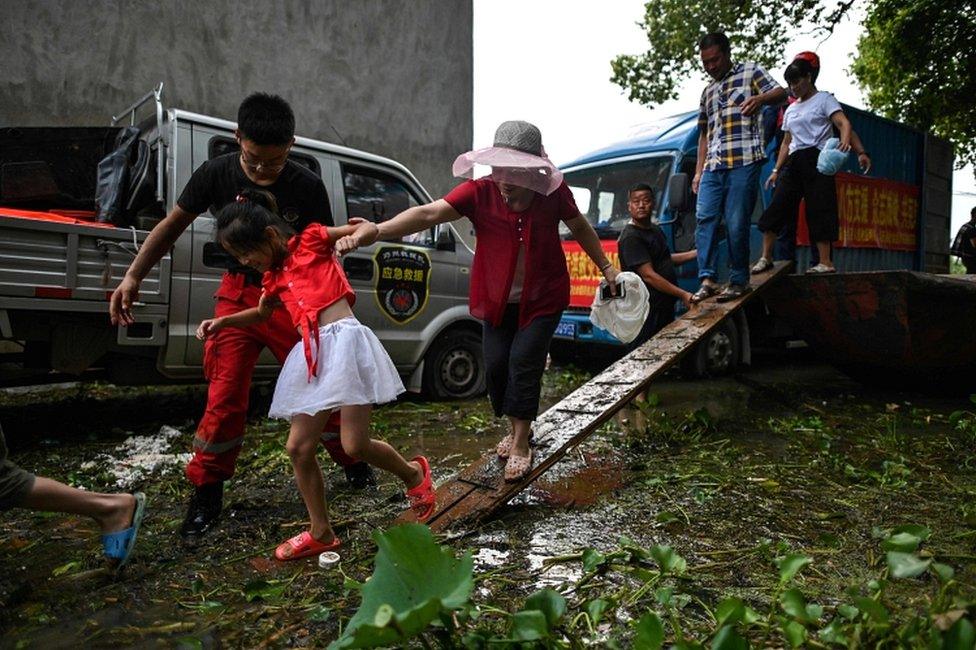 Residents get off a boat in a flooded area in Longkou village due to torrential rains in Poyang county, Shangrao city, in China's central Jiangxi province on 16 July 2020