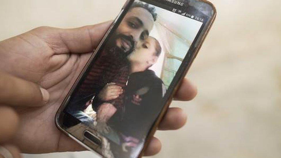 A hand hold a phone which shows a photo of Nidhal Gharibi