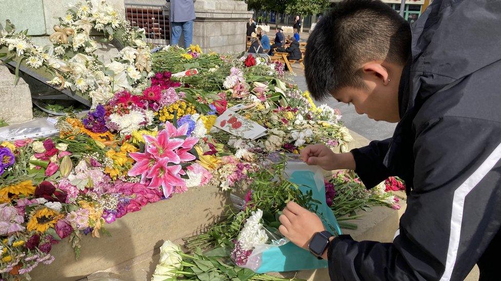 Sam Chan leaving flowers at statue in Hull