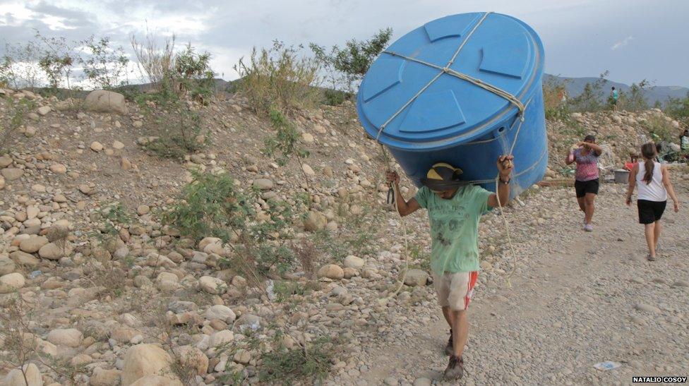 A man carries a huge containers on his shoulders near the Tachira river on the Colombian-Venezuelan border