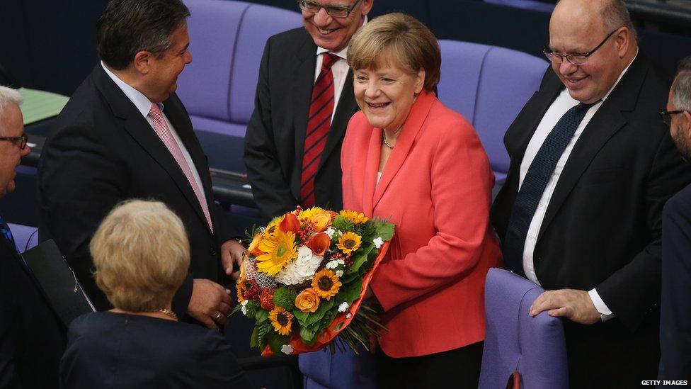 German Chancellor Angela Merkel receives flowers and congratulations on her birthday prior to debates and votes over the third EU financial aid package to Greece at an extraordinary session of the German parliament, the Bundestag, 17 July 2015