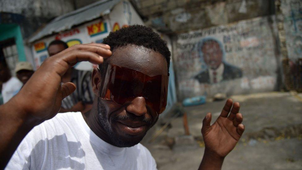 A man uses glasses he made from a plastic bottle to look the solar eclipse that was partially visible in Port-au-Prince, on August 21, 2017. The solar eclipse in Haiti was only partially visible, around a 73% in the north of the country, and around a 70% in the capital.