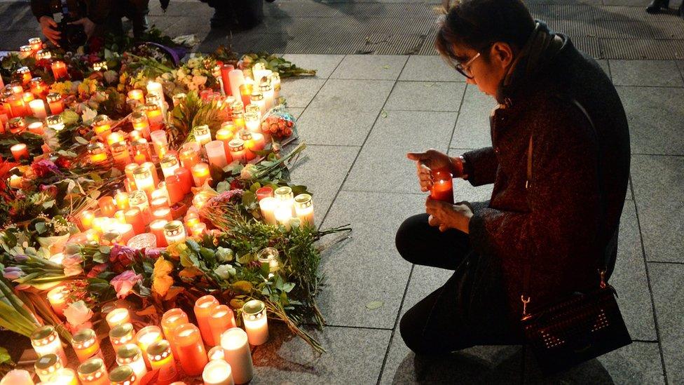 A man lights a candle to pay tribute to the victims at the site of the lorry attack in Berlin, Germany, 20 December