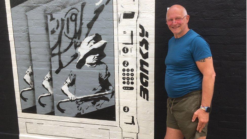 Joe Thompson with his version of the Banksy mural