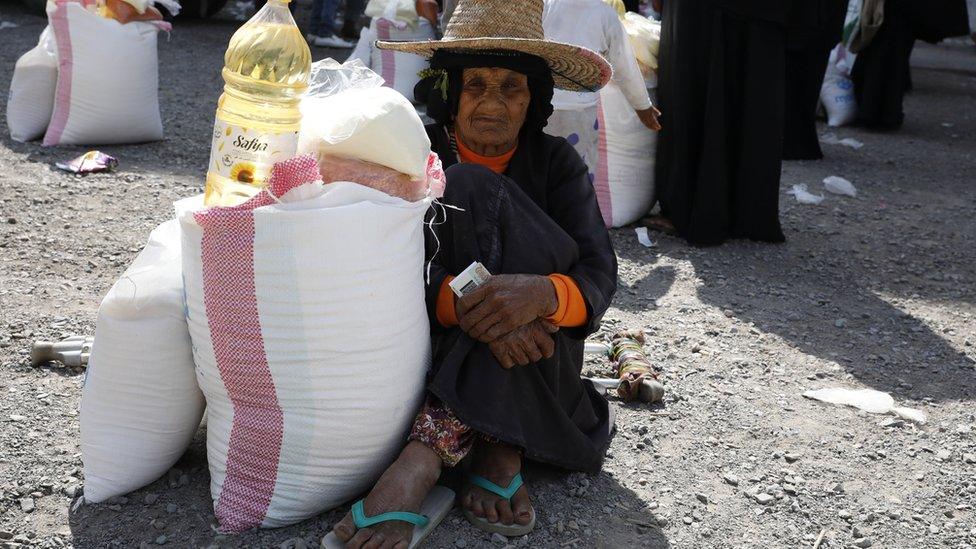 An elderly Yemeni woman gets her family's food ration provided by a local aid group, Mona Relief Yemen, in the western port city of Hudaydah, Yemen, (7 January 2021)