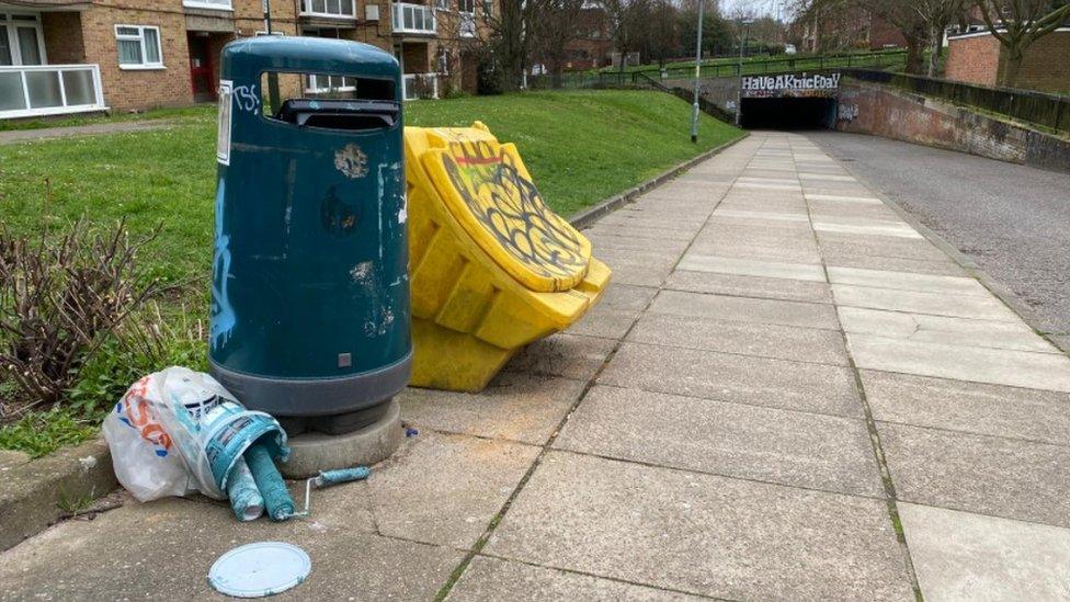 Discarded paint and rollers near the defaced mural