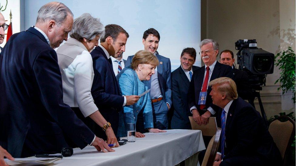 G7 leaders gather in a tight crowd around a narrow table