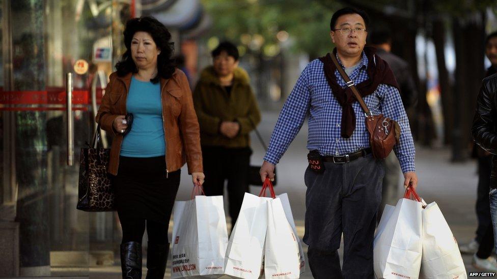 A Chinese couple carrying shopping bags as they walk outside a mall in Beijing