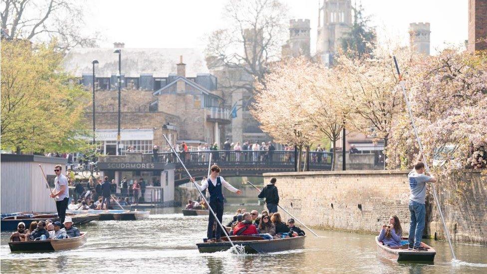 People punting and walking along a bridge in Cambridge