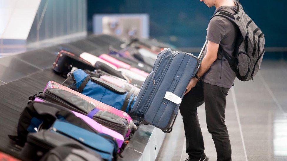 Traveller lifting suitcase from luggage carousel at an airport