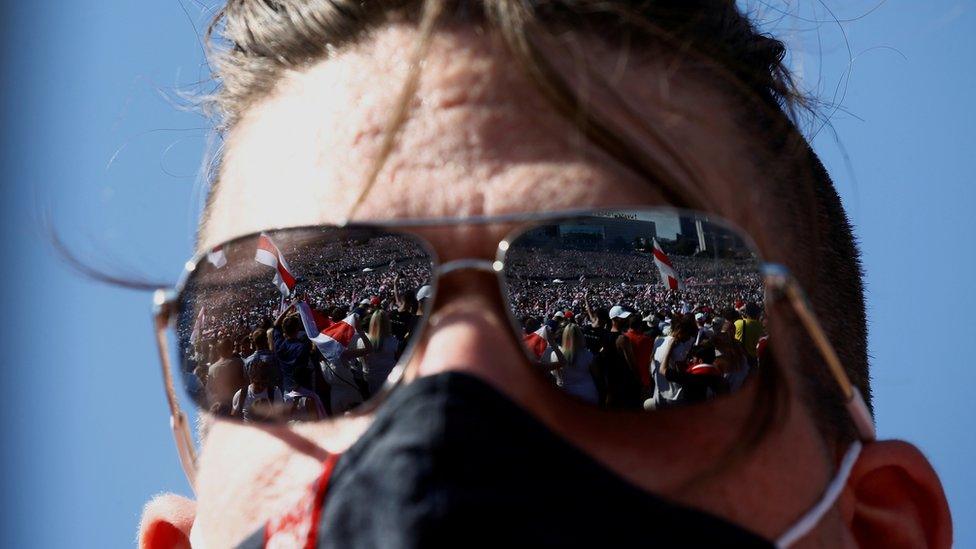 Demonstrators are reflected in the sunglasses of a participant during a protest against the presidential election results