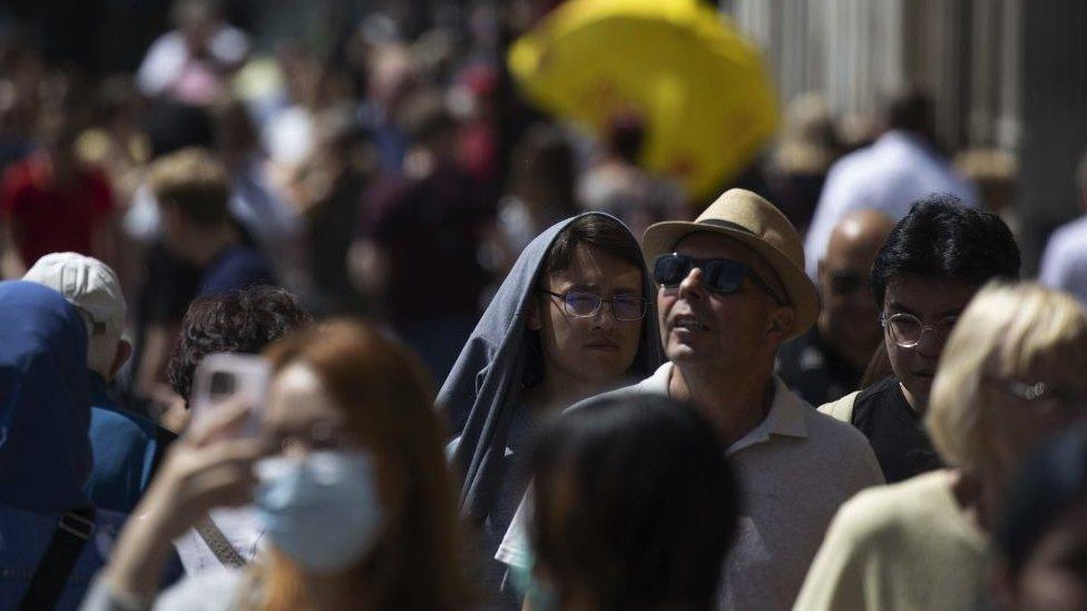 street crowd scence of people protecting themselves from the Sun.