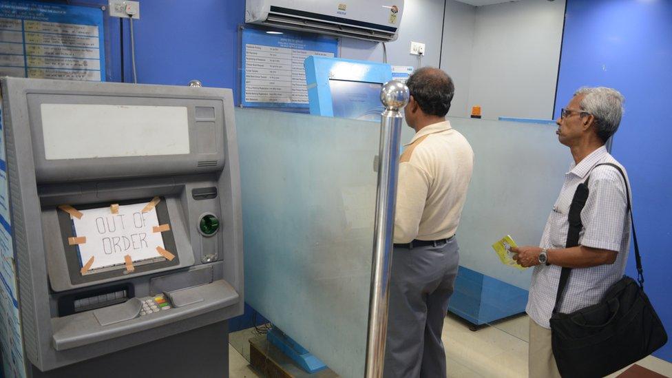 Indian customers update their passbooks at a State Bank of India ATM in Siliguri on November 21, 2016.