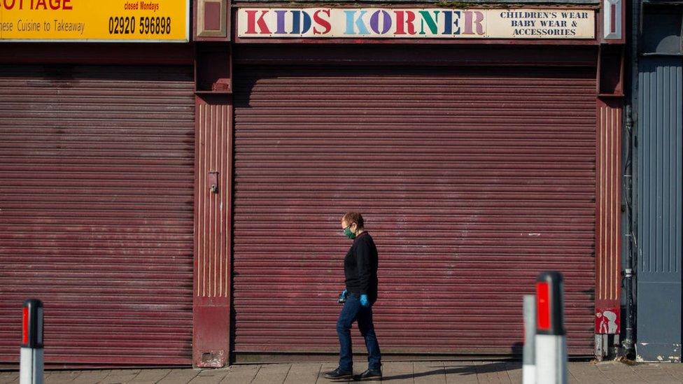 man in mask walking past closed shop