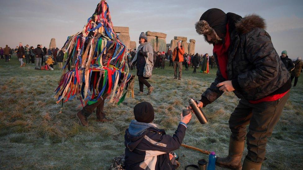 People greet the sunrise at Stonehenge