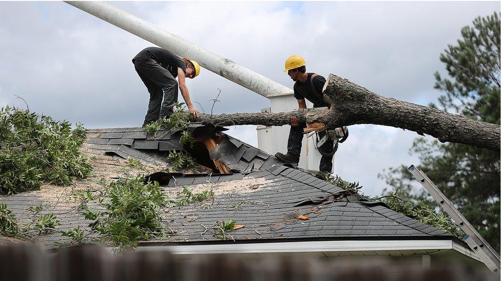 A tree service company removes a fallen tree from the roof of a damaged home Friday, Sept. 2, 2016, in Valdosta. Ga., in the aftermath of Tropical Storm Hermine.