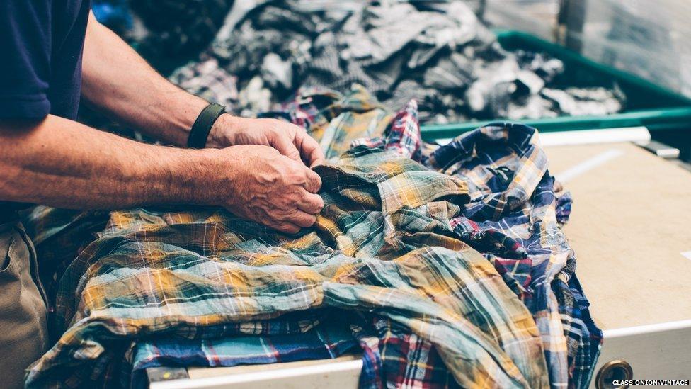 A man doing up the buttons of a shirt