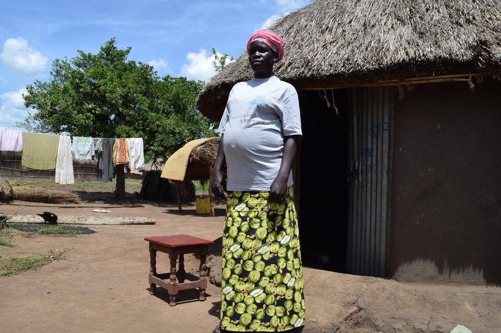 Keji stands outside her house