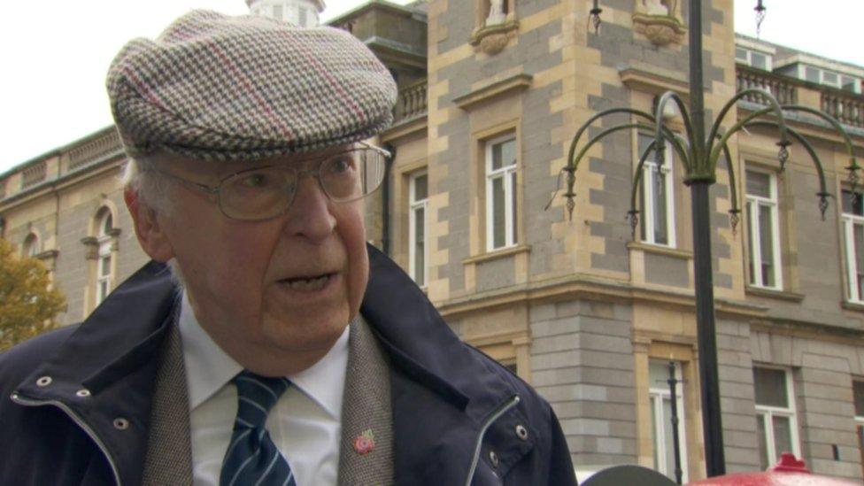 Gerry Burns wearing glasses and a tweed cap