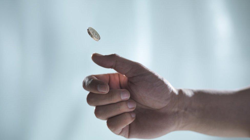 A hand flipping a coin