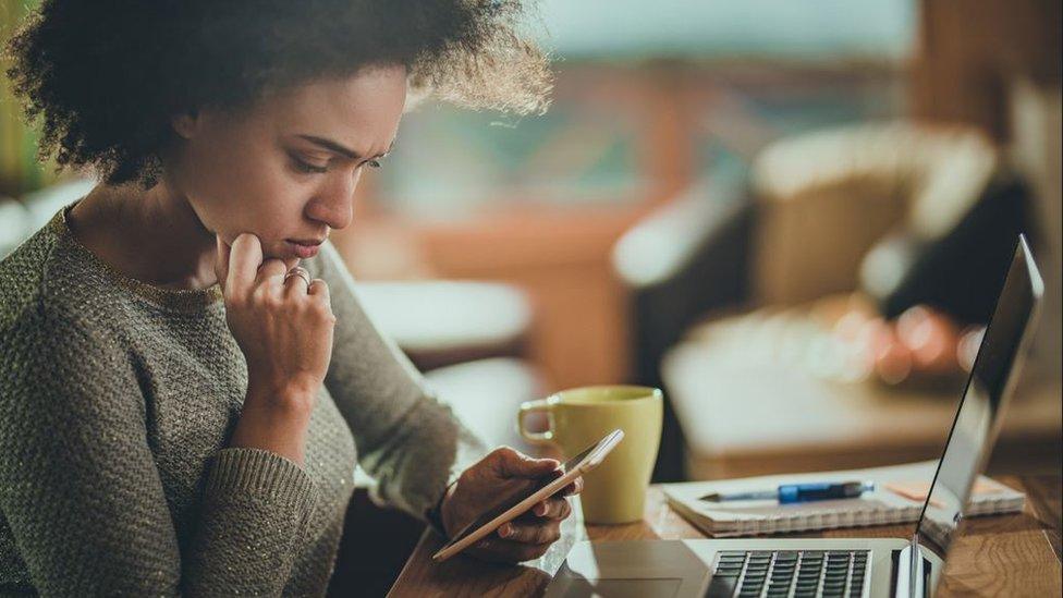 Woman reading a text while working on her laptop