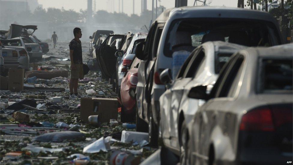 A man looks at a row of damaged cars outside a residential building near the site of a series of explosions in Tianjin, northern China on 13 August 2015