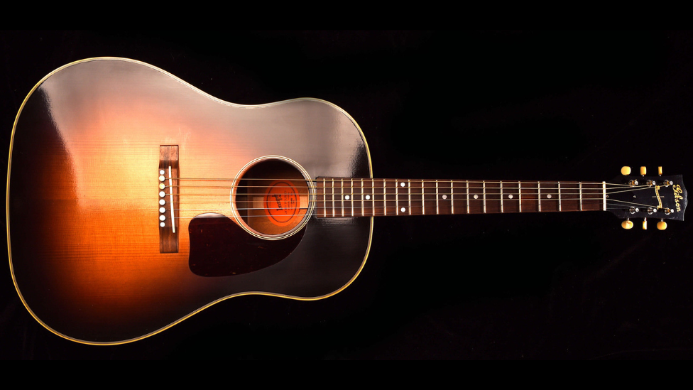 A Gibson J-45 acoustic guitar on a black background