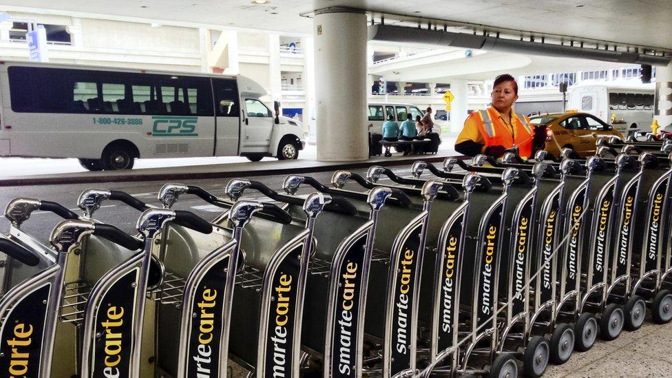 Woman arranging luggage carts at the entrance to International Terminal of Los Angeles Airport