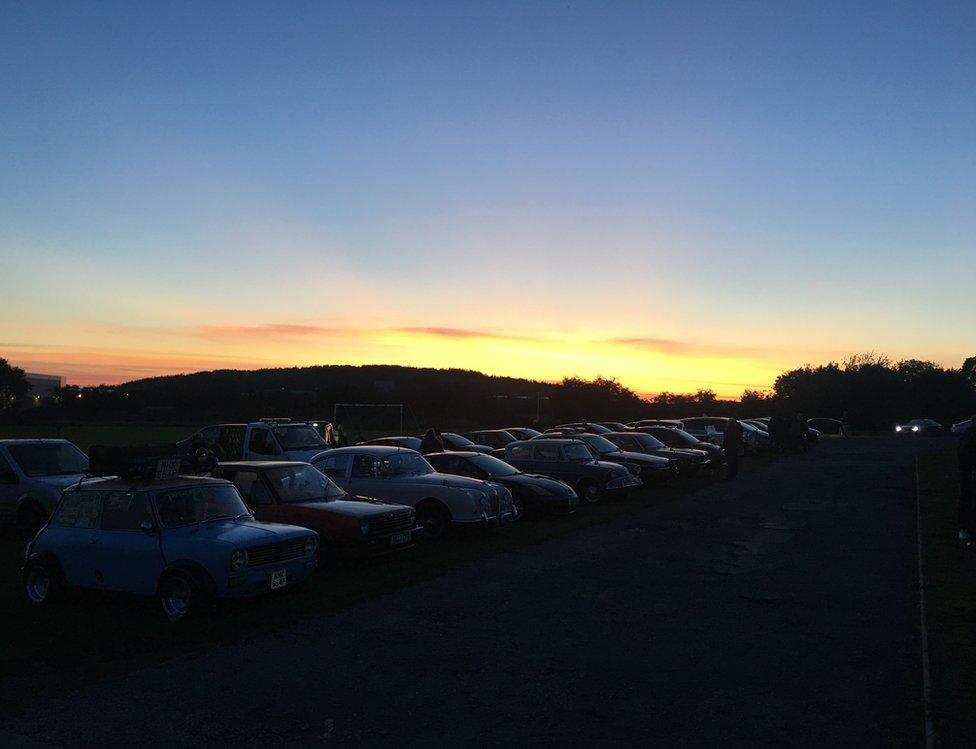 Sunset over a field with cars in