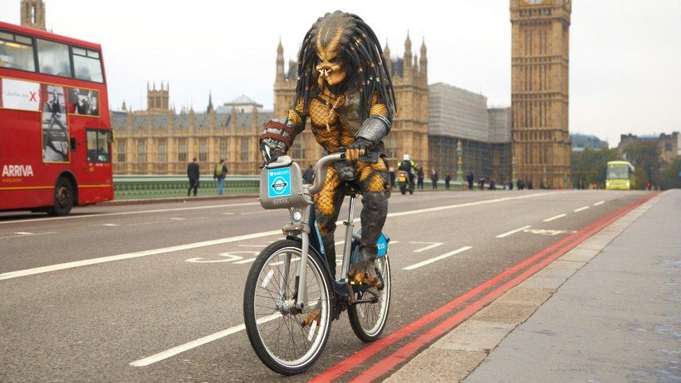 Person dressed as Predator on bike