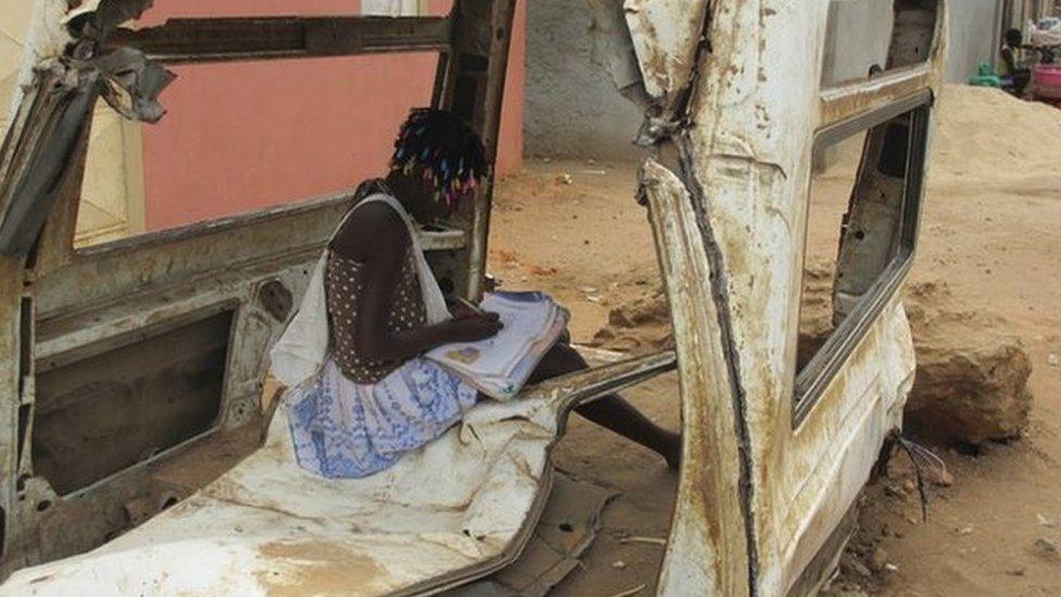Child doing homework in wreck of car