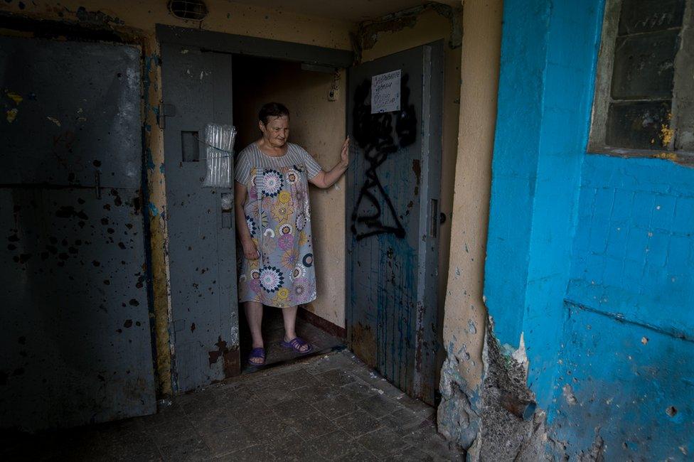 Nadia Kravchuk looks down at damage from a munition that killed two of neighbours (Joel Gunter/BBC)