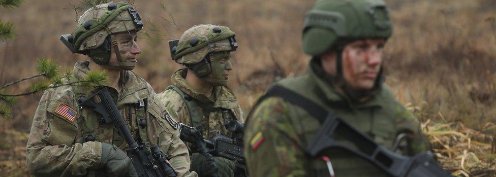 Members of the U.S. 173rd Airborne Brigade (L) and a Lithuanian infantry soldier participate in the Iron Sword multinational military exercises on November 24, 2016 near Pabrade, Lithuania