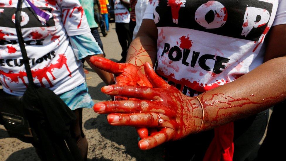 A member of the civil society smears her hands with mock blood as others chant slogans, during a protest dubbed "Stop extrajudicial killings" on the killing of human rights lawyer, Willie Kimani, his client and their driver in Nairobi, Kenya, July 4