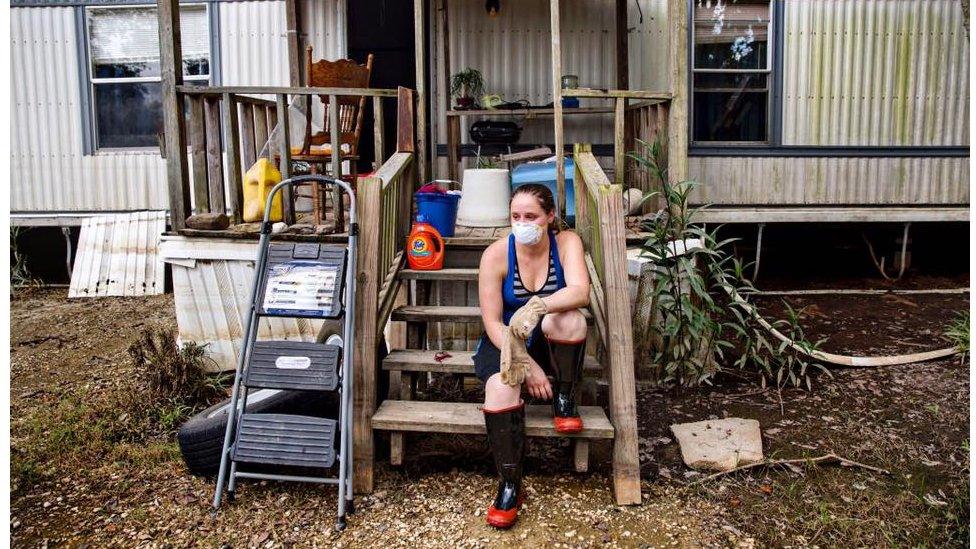 Stephanie M, 29, takes a break from cleaning her parents' home in St Amant. One of the items they saved is her great-grandmother's table, which had already been restored several times and will now need more repairs. "I have three family members living with us. They don't know what they're going to do," she said. "My mom is not coming back here. It's just too much. They are going to stay as long as they need to."