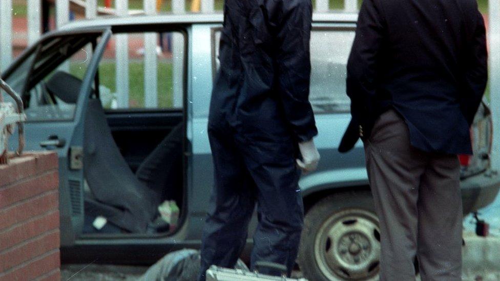 Scene shows police at a car murder scene with body partially visible on floor.