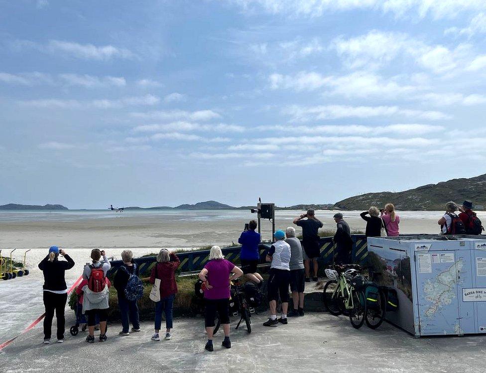 Crowds watch a plane landing at the beach