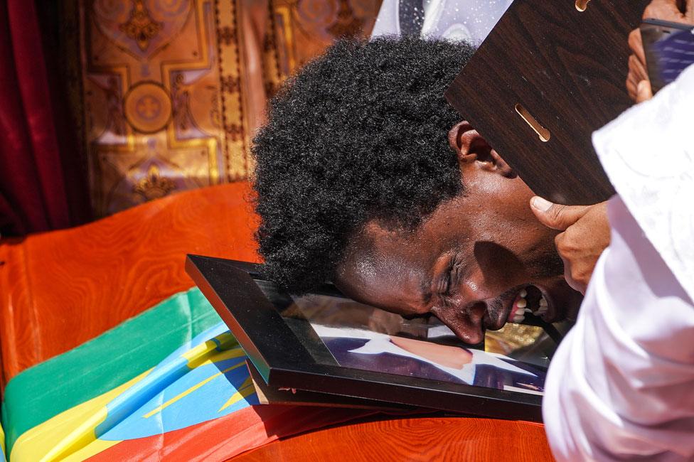 A mourner cries on the coffin of his loved one during a memorial service for the Ethiopian passengers and crew who perished in the Ethiopian Airways ET302 crash