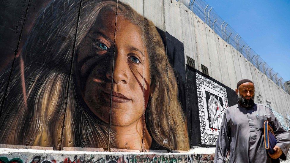 A Palestinian walks past a mural painted on Israel's controversial separation barrier in the West Bank city of Bethlehem on July 29, 2018