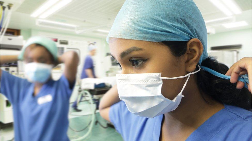 Two women wearing scrubs and PPE in hospital